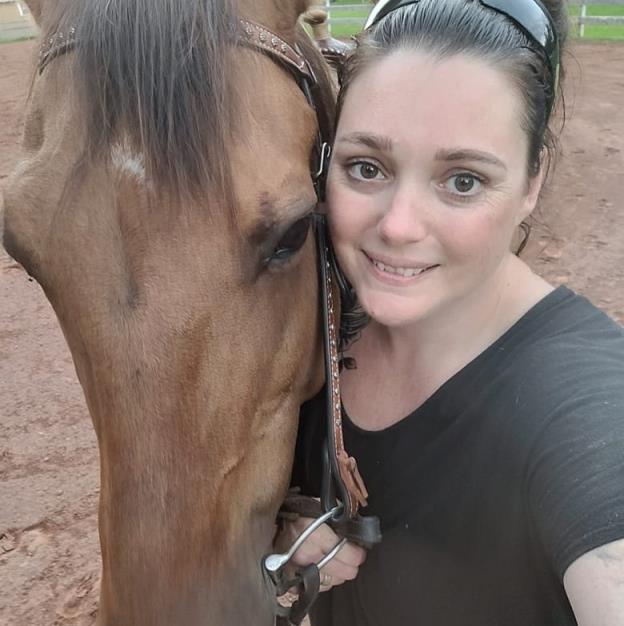 A woman smiles next to a horse